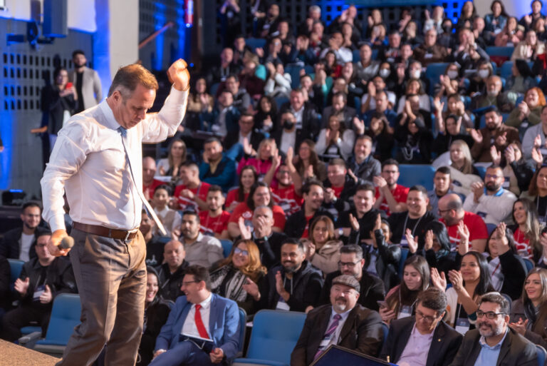 Palestrante motivacional falando com energia para uma plateia lotada em palestra motivacional para empresas